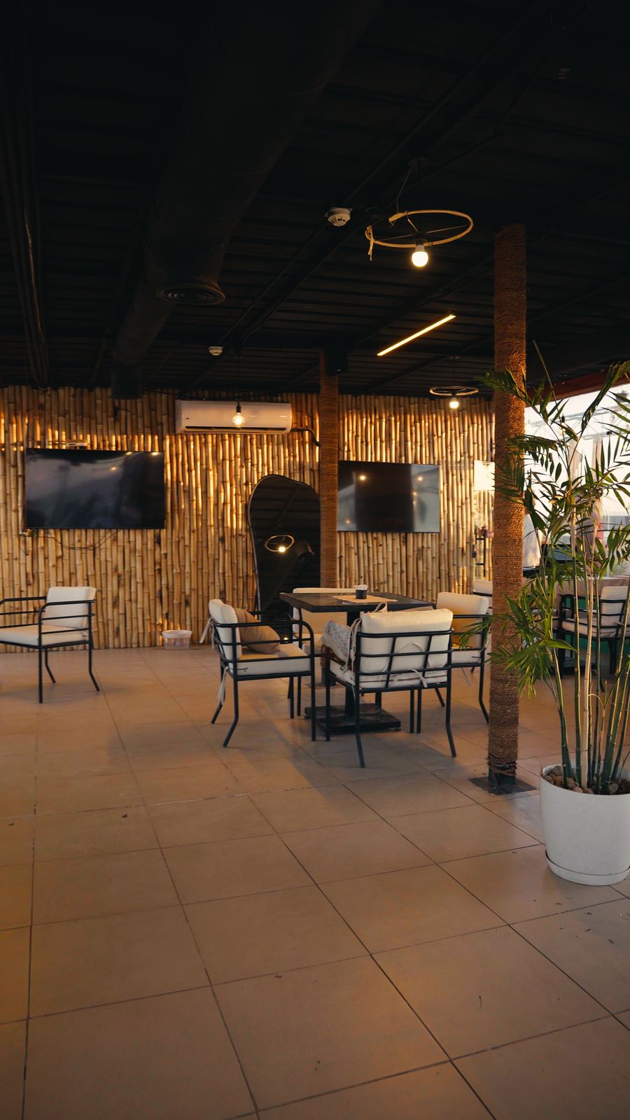 Bamboo-walled lounge with a big screen and rooftop tables