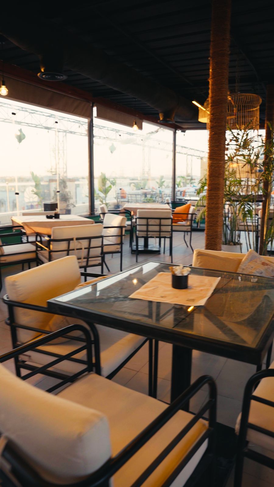 Glass-topped tables and cushioned chairs at golden hour